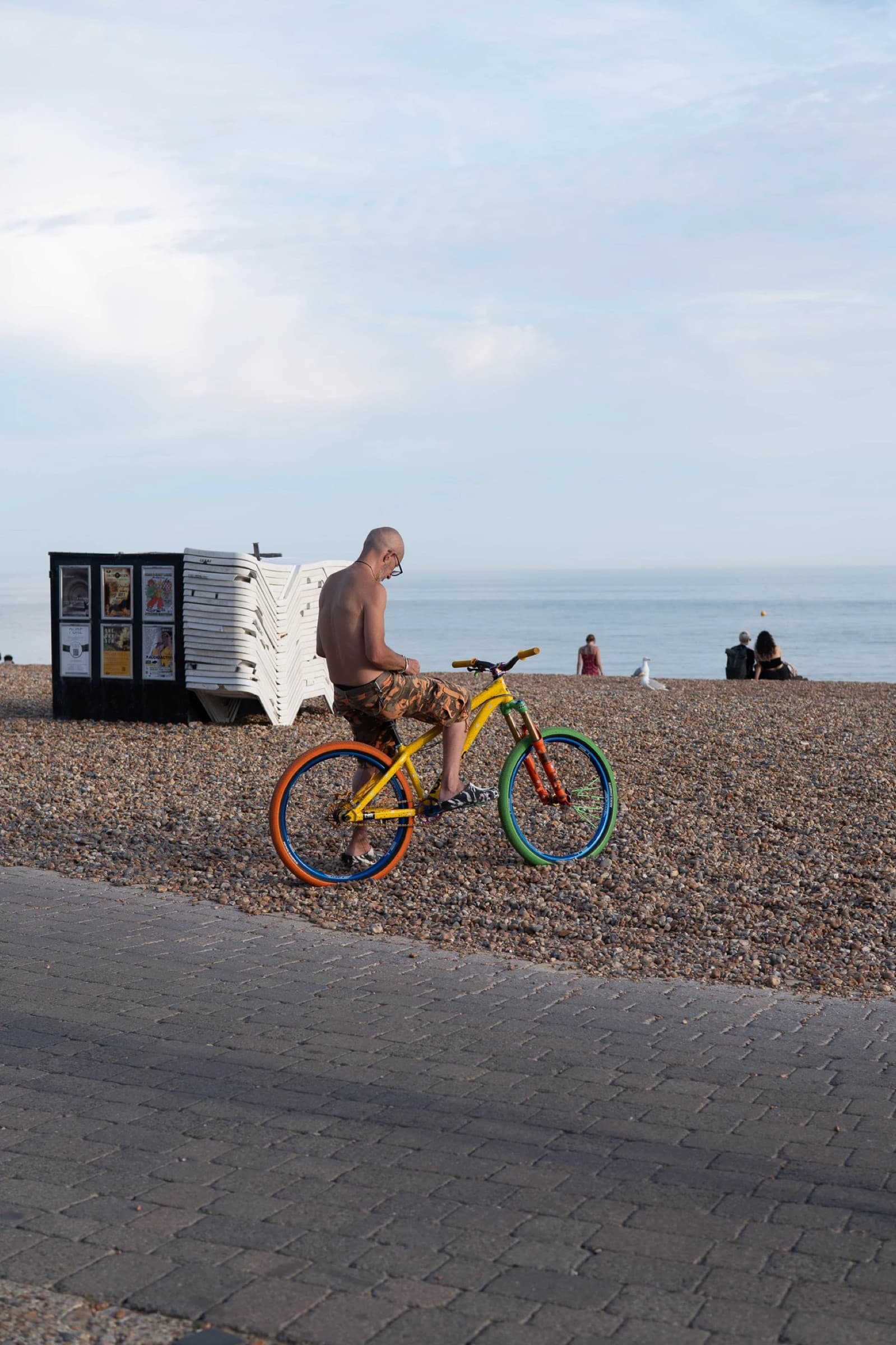 A cyclist on a painted bike on Brighton beach, before editing